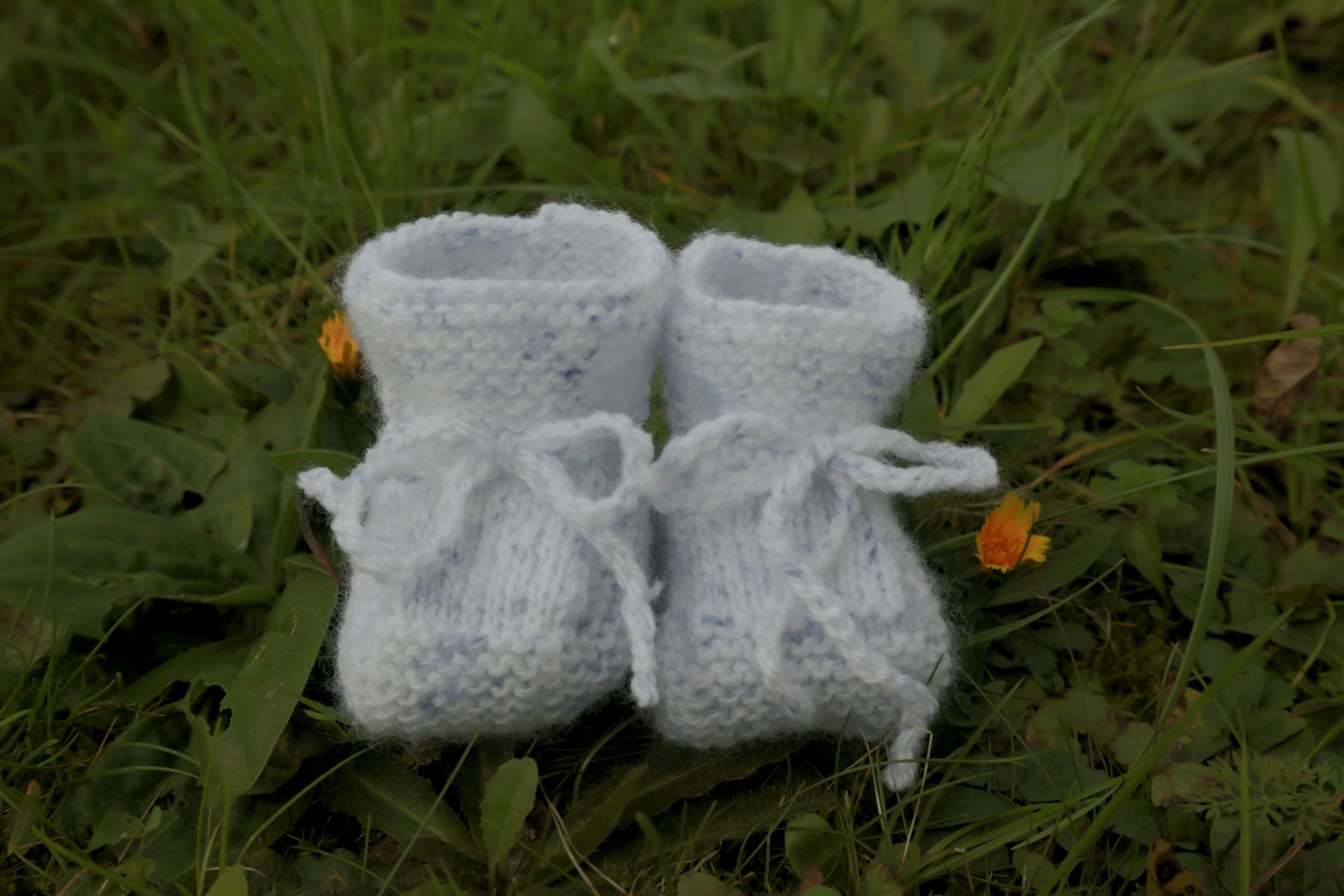 Gestrickte Kinderschuhe liegen im Gras